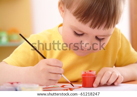 Cute cheerful child draws with paints in preschool, shallow depth of field