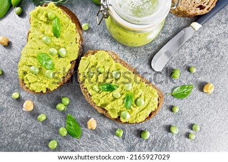 Hummus sandwiches with green peas and chickpeas, jar of dipping sauce, pea pods on stone tabletop background from above Foto stock © 