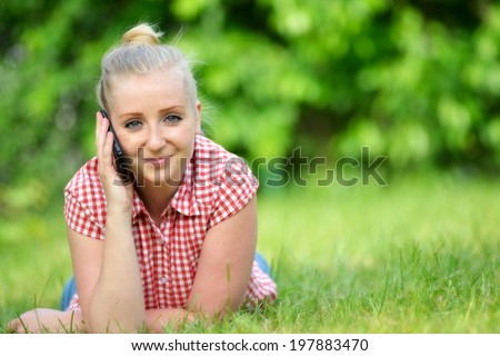 Young attractive woman lying on lawn with phone.  MANY OTHER PHOTOS FROM THIS SERIES IN MY PORTFOLIO.