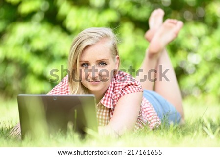 Young attractive woman lying on lawn with laptop. MANY OTHER PHOTOS FROM THIS SERIES IN MY PORTFOLIO.