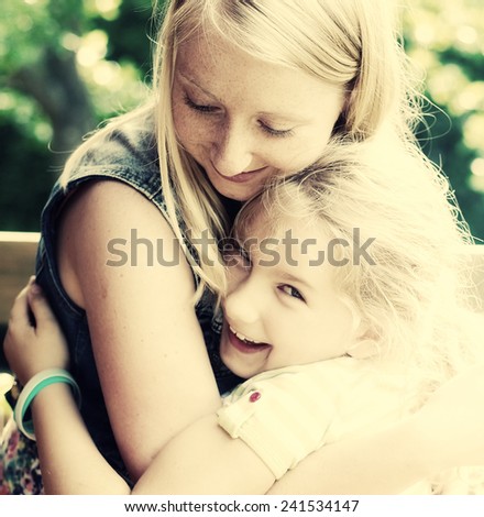 Young mother and daughter. Happy family in garden.