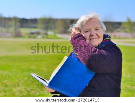 Senior happy woman sitting on on glade and reading book in the park. Healthy outdoor activities. Happy and smiling. MANY OTHER PHOTOS FROM THIS SERIES IN MY PORTFOLIO.