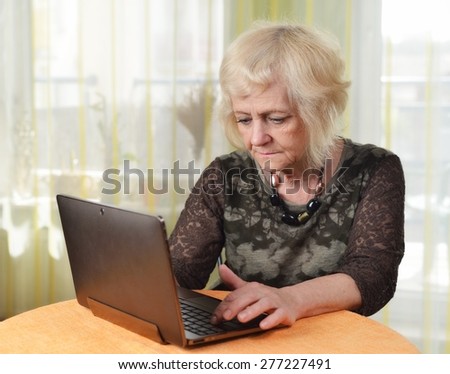 Mature woman with laptop in her room. MANY OTHER PHOTOS FROM THIS SERIES IN MY PORTFOLIO.