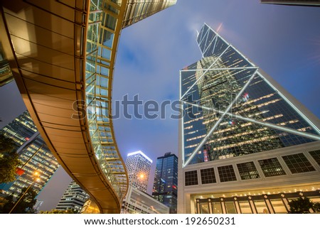 Hong Kong by night. Pedestrian passage over street level and surrounding majestic skyscrapers of downtown. Wide angle view.