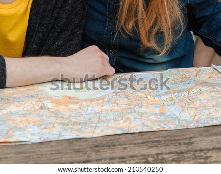 Couple checking city map outdoor. Detail on hands.