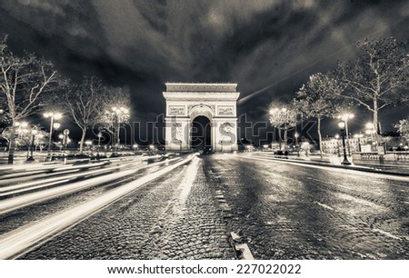 Traffic flow in Paris. Car light trails in front of Arc de Triomphe.