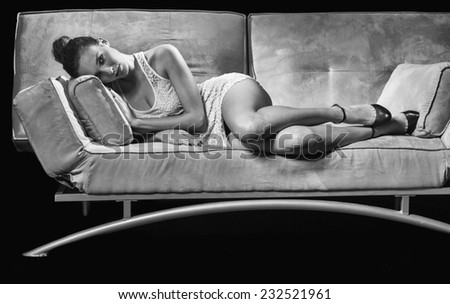 Beautiful young woman laying on the sofa smiling and thinking.