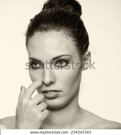 Beautiful girl scratching her nose with finger. Reflection and doubt concept.