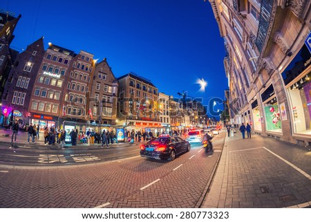 AMSTERDAM - APRIL 25, 2015: Tourists and locals along city streets at night. Amsterdam attracts almost 10 million people annually.