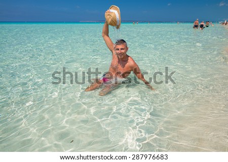 Happy man relaxing with straw hat on turquoise water.