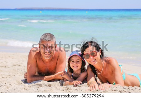 Father mother and daughter relaxing and smiling laying on a beautiful beach.