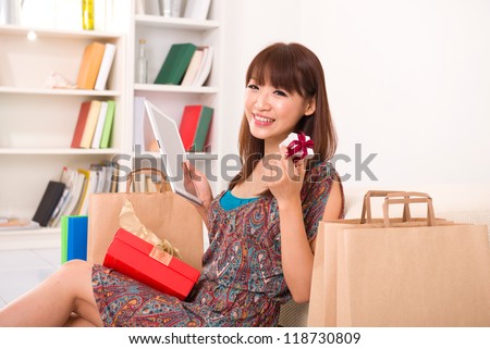 asian girl enjoying online shopping from home, showing off a present