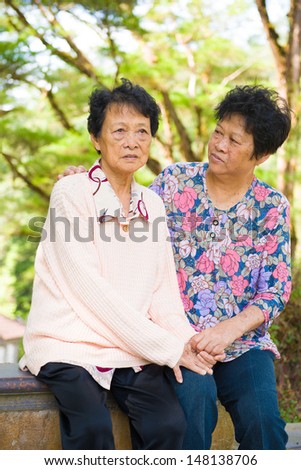 crying Asian senior mother with her senior daughter at outdoor park