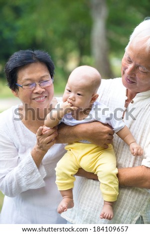 asian baby sucking hand while being carried by grandfather