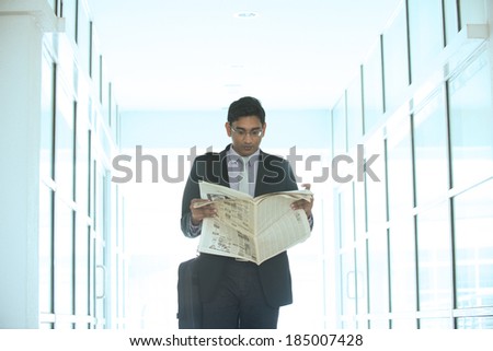 indian business male reading paper and walking