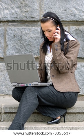 Business lady with laptop talking to mobile phone