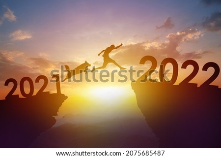 Dog jumping with owner to new year 2022 at top of mountain with beautiful sunset.