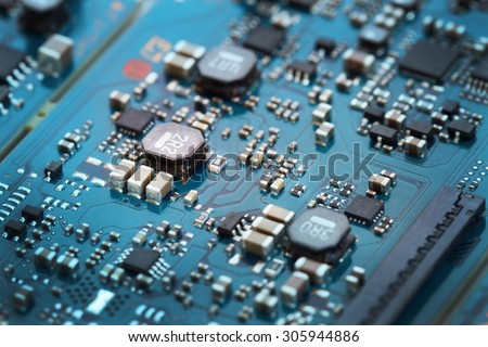 Closeup electronic circuit board, blurred and toned image. Shallow DOF, focus at three capacitor chip on the left.