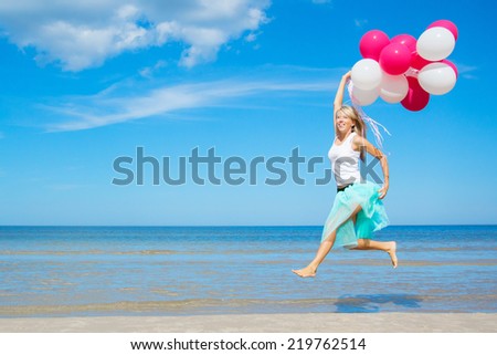 Happy woman holding balloons and jumping in the air