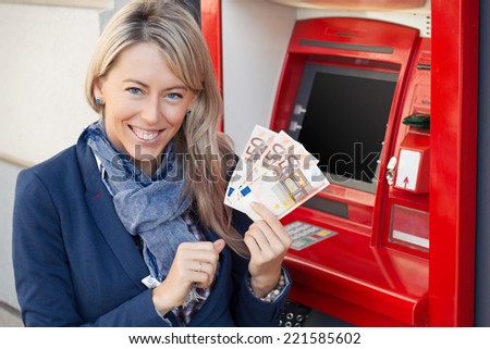 Happy woman withdrawing cash from ATM