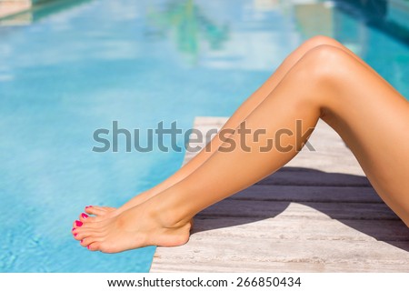 Beautiful tanned women legs by the swimming pool