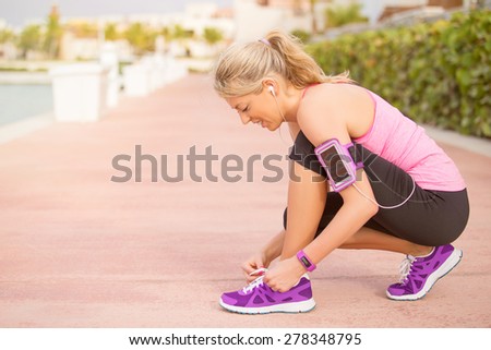 Active sporty girl tying shoes before morning workout