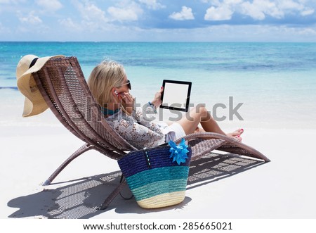 Woman relaxing on the beach and listening to music on her digital tablet computer