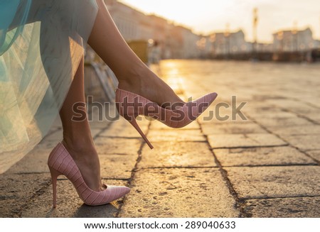 Woman in high heel shoes in city by sunrise