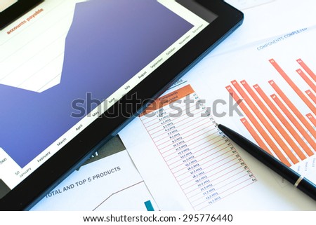 Office table,charts and diagrams shown on tablet and papers