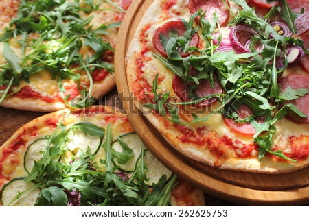 Pizza with sausage, zucchini, olives, cheese, rucola