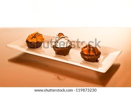 Three handcrafted brownie bites on a white rectangle plate with focus on the center brownie.  Isolated white background.
