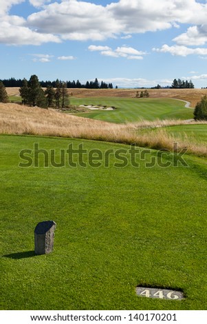 The tee off spot for a professional golfer showing a distance of four hundred forty six yards to the hole on a naturally landscaped golf course.