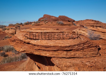 Layers of Arizona desert sand, that at one time had formed this large sandstone rock, are now eroding back to the sand that it once was.