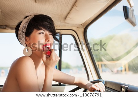 pretty woman looking in rear view mirror and putting make up in car