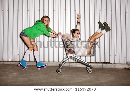 Happy two naughty women with shopping cart. outdoors