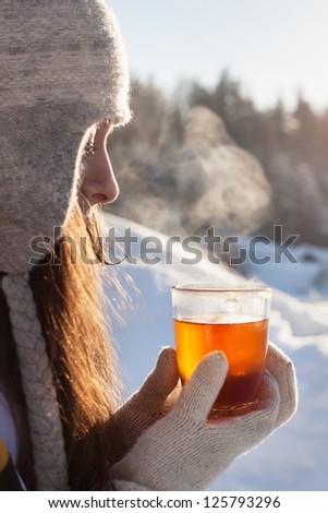 girl  drinks tea over winter nature background outdoor
