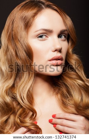 Beauty face of woman with clean skin and long golden hair on dark background