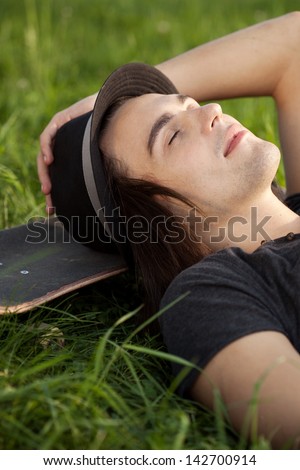 Young man lying down on his skateboard. Outdoor, lifestyle
