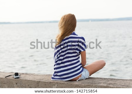 Young woman with old camera sitting on the sea background. Outdoor, lifestyle