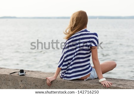 Portrait of beautiful young woman with old camera sitting on the sea background. Outdoor, lifestyle