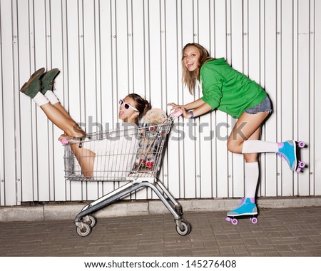 Happy two naughty women with shopping cart. outdoors