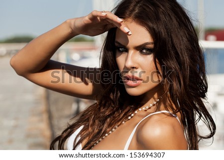 Beautiful woman  sitting in the hot sun on the pier near the boats and yachts. Outdoors, lifestyle