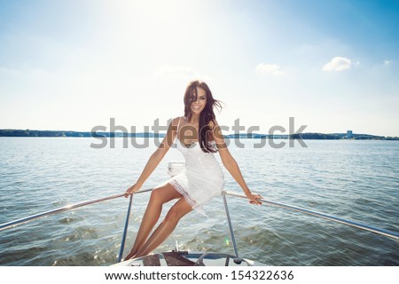 Young happy beautiful woman looking at the camera on the luxury boat in open sea in summer. Caucasian female model. Outdoors, lifestyle.