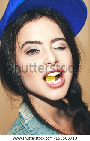 Young sexy brunette woman biting gelatin candy and winking.