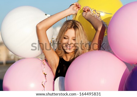 Happy young woman having fun with big colorful latex balloons. Outdoors, lifestyle