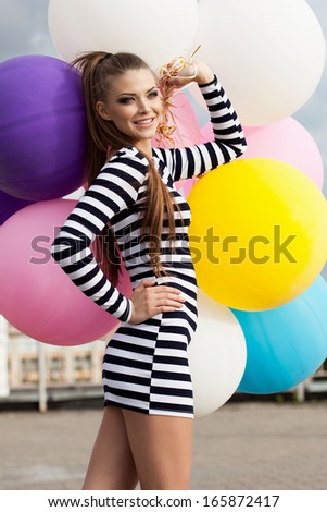 Happy young beautiful woman standing with colorful latex balloons. Outdoors, lifestyle