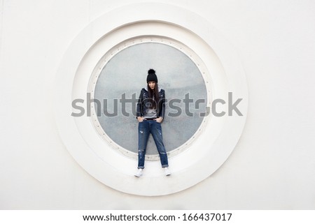 Portrait of a beautiful girl hipster. Young woman posing against a wall in the shape of a circle. Outdoors, lifestyle.