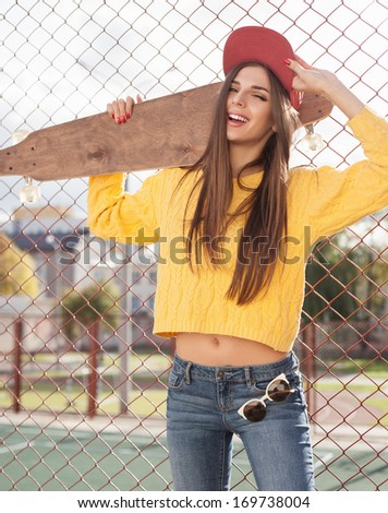 Beautiful young girl  hipster standing with longboard near playground in the afternoon. Skateboarding. Outdoors, lifestyle