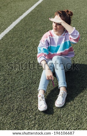 girl sitting after training in stadium, outdoors