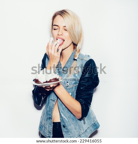 Pretty blonde girl eating chocolate Cake. Indoor lifestyle portrait of woman in sunglasses.  White background, not isolated